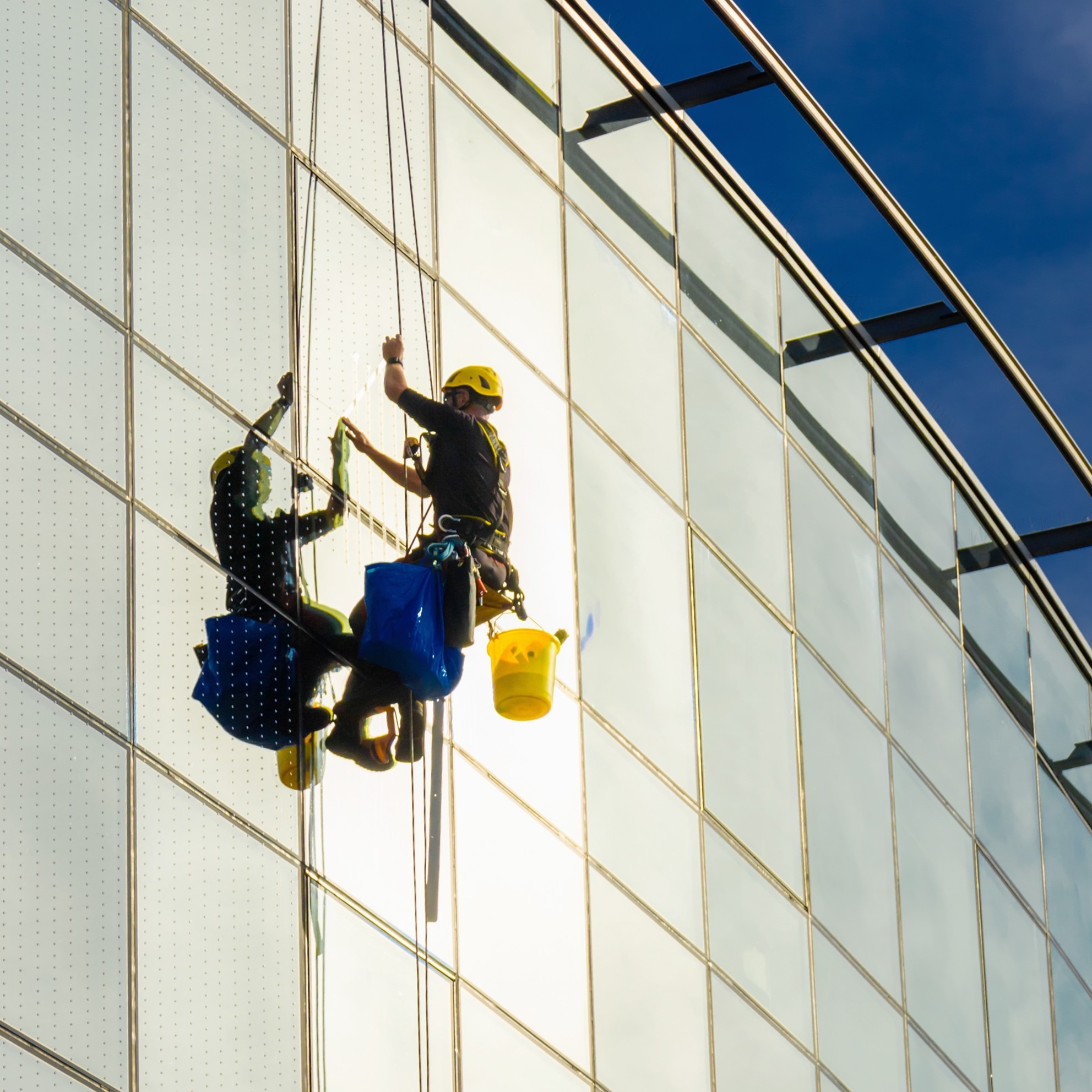 industrial climber washes mirror glass in a modern building